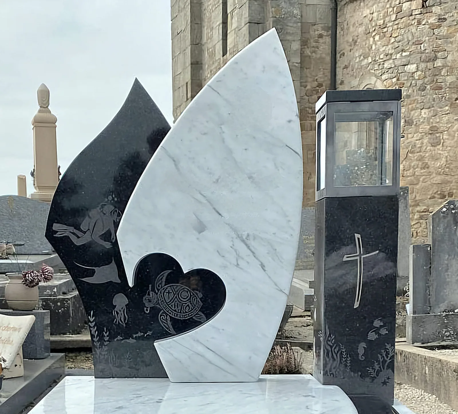 Monument funéraire en granit noir poli et marbre blanc, entretenu, dans une allée de cimetière